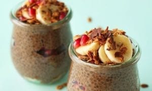 Two jars of overnight chocolate chia seed pudding topped with bananas, apples, and nuts