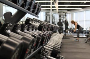 Woman exercising in a gym with weights; Exercise can help to manage the symptoms of seasonal affective disorder
