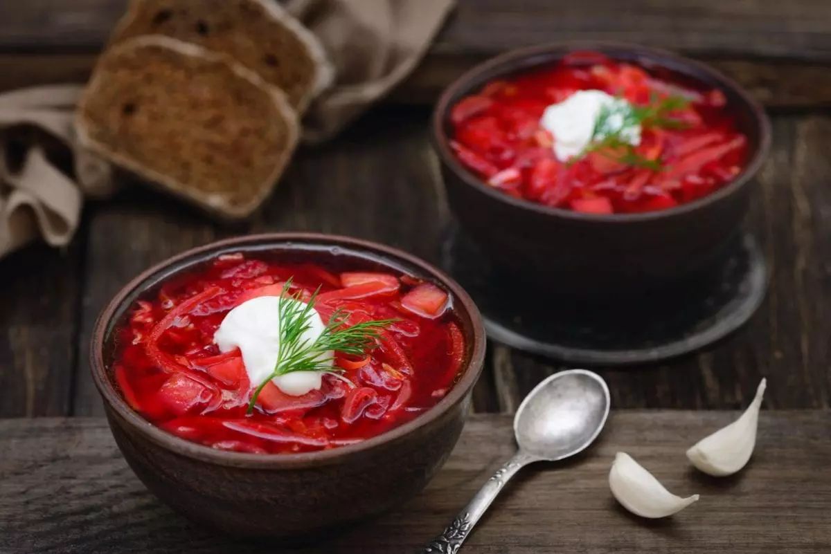 Vegetarian red beet borscht soup in bowls on an old wooden background