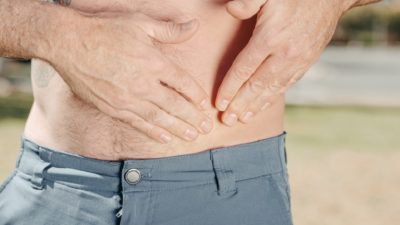 closeup of a mans hands on his stomach due to a stomach ache from irritable bowel syndrome