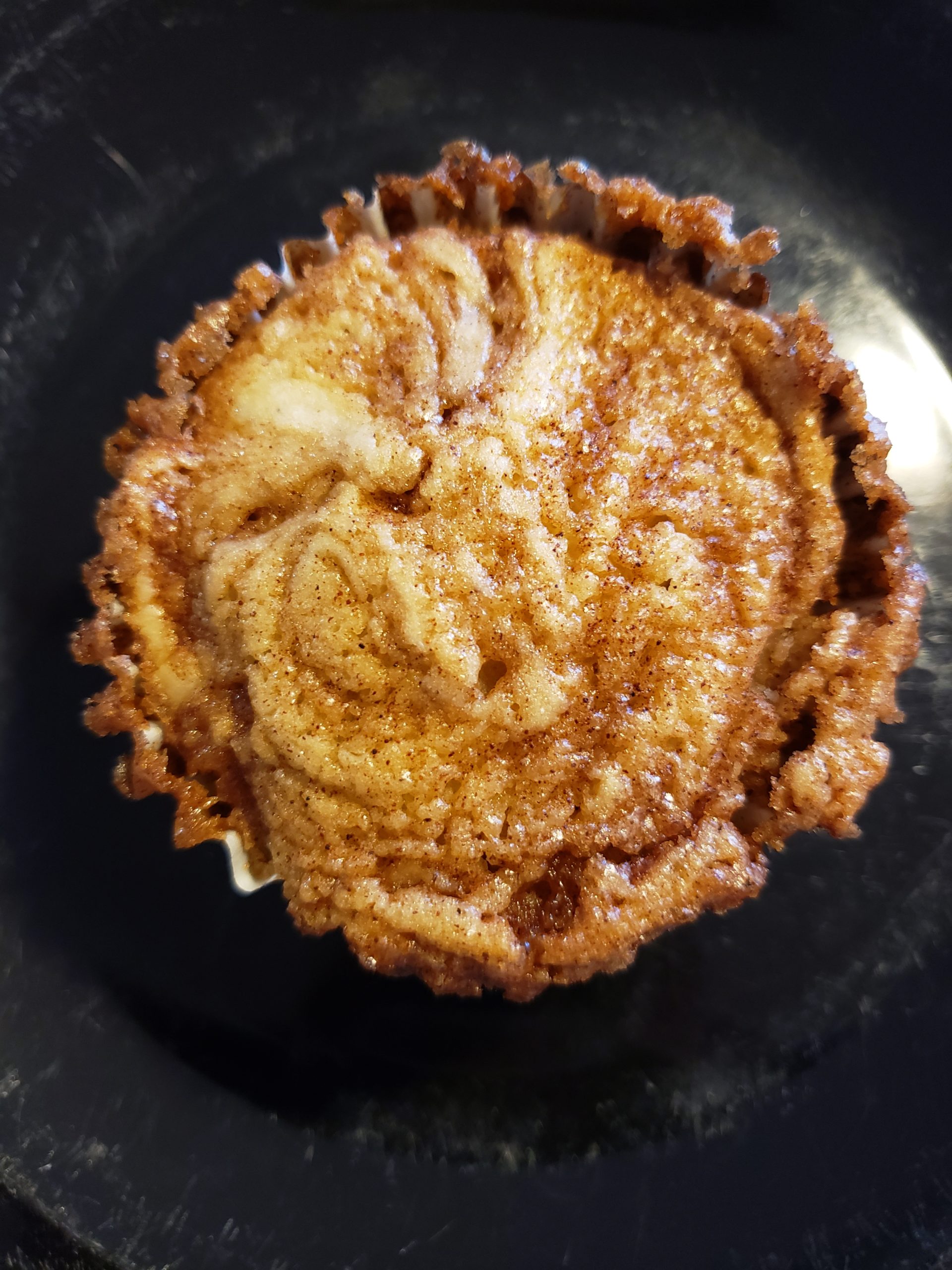 gluten-free cinnamon roll muffin in a muffin pan with browned top