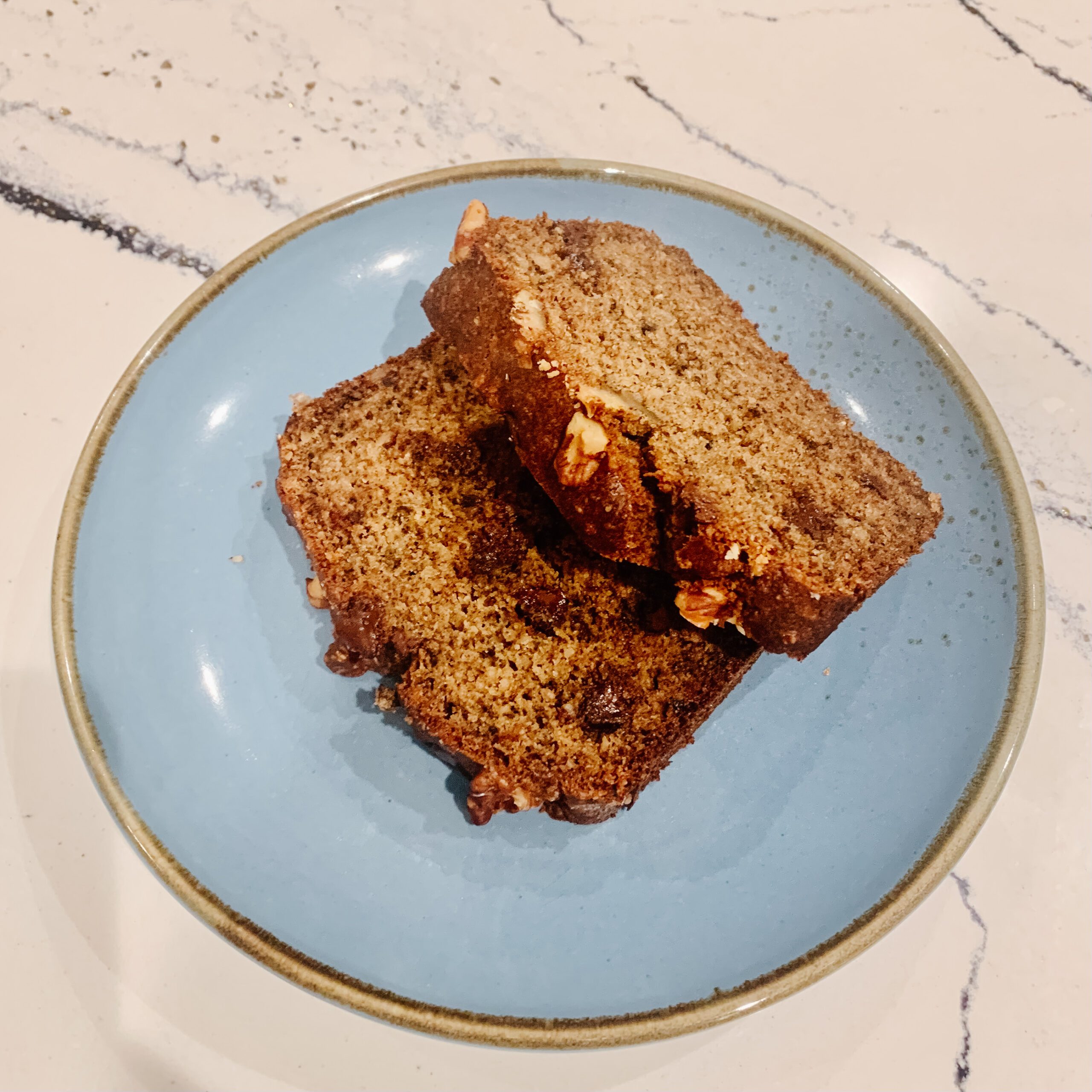 blue plate on a marble countertop with two slicces of gluten-free banana bread