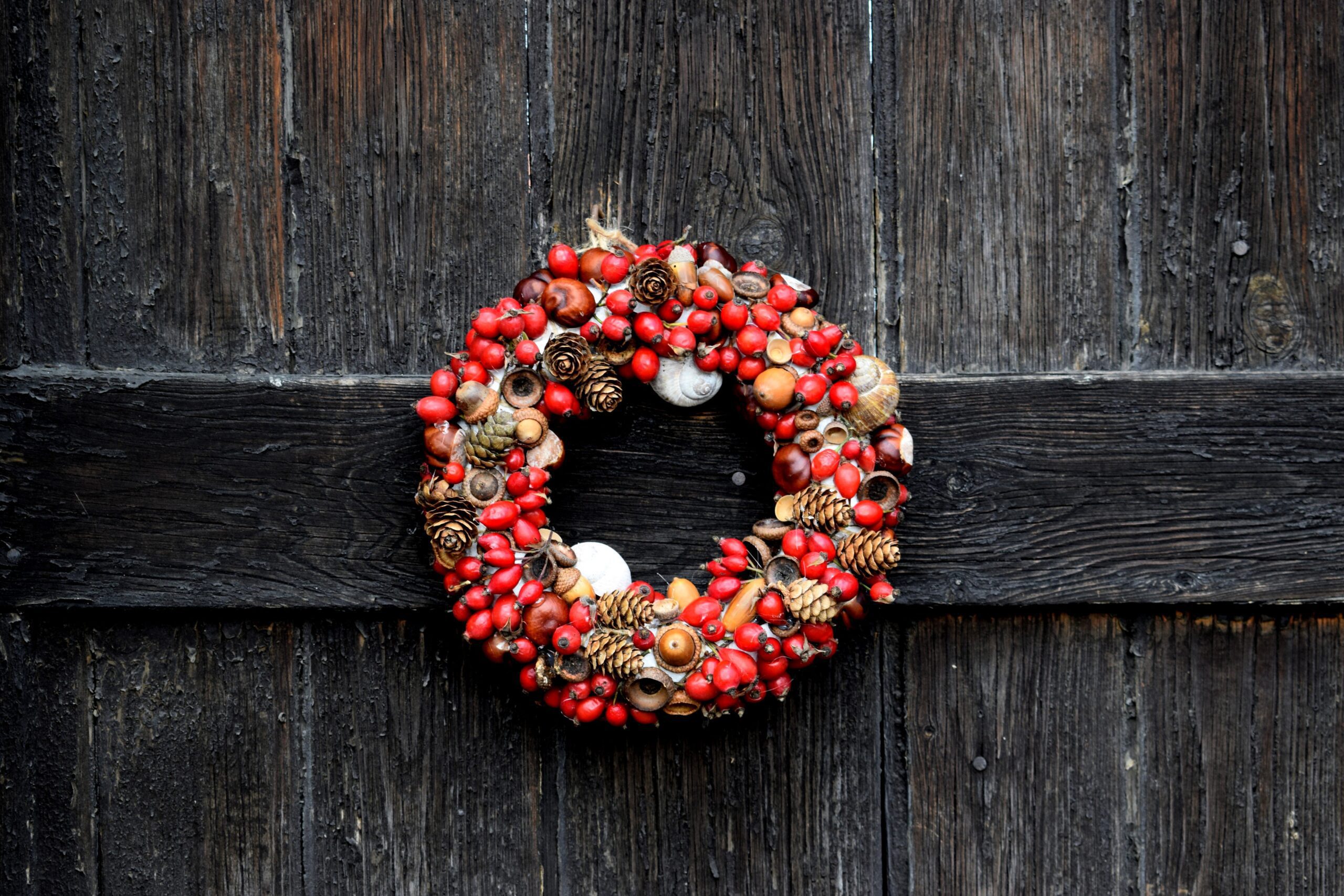 Red holiday wreath on a wood background, highlighting holiday hacks to relieve stress over the holidays